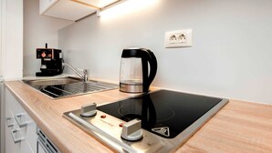 Une cuisine moderne équipée d’une plaque de cuisson à induction noire, d’une machine à café et d’un évier.