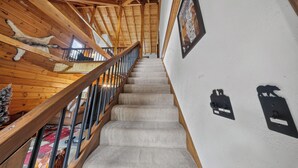 Eine Holztreppe mit Geländer, Teppichstufen und an der Wand befestigten Lichtschaltern.