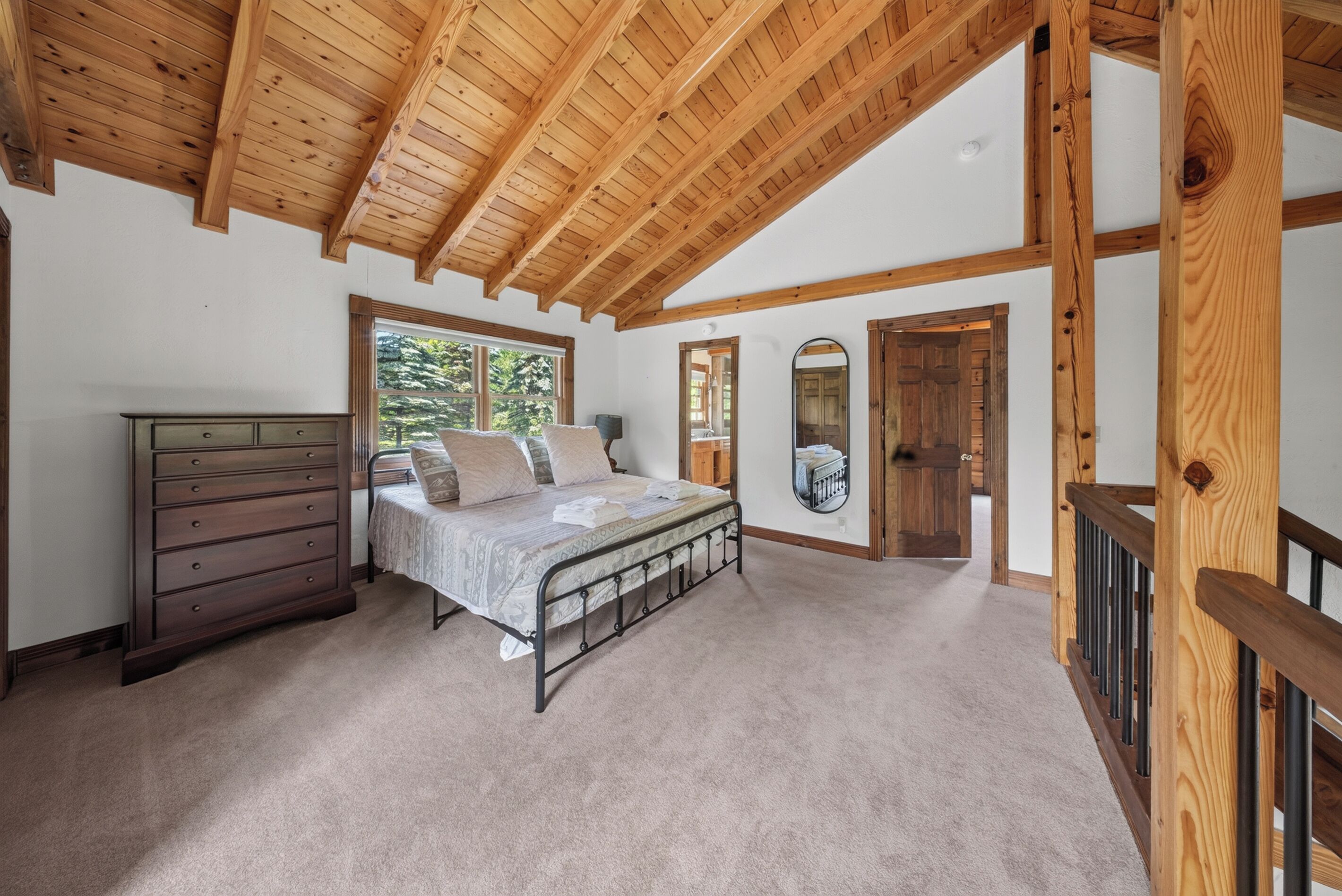 A bedroom with a bed, dresser, and a large window.
