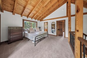 A bedroom with a bed, dresser, and a large window.