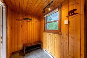 Puinen mökki sisältä, siellä on penkki, ikkuna, josta on näkymä, ja kyltti, jossa lukee: ”Bear Yung”.