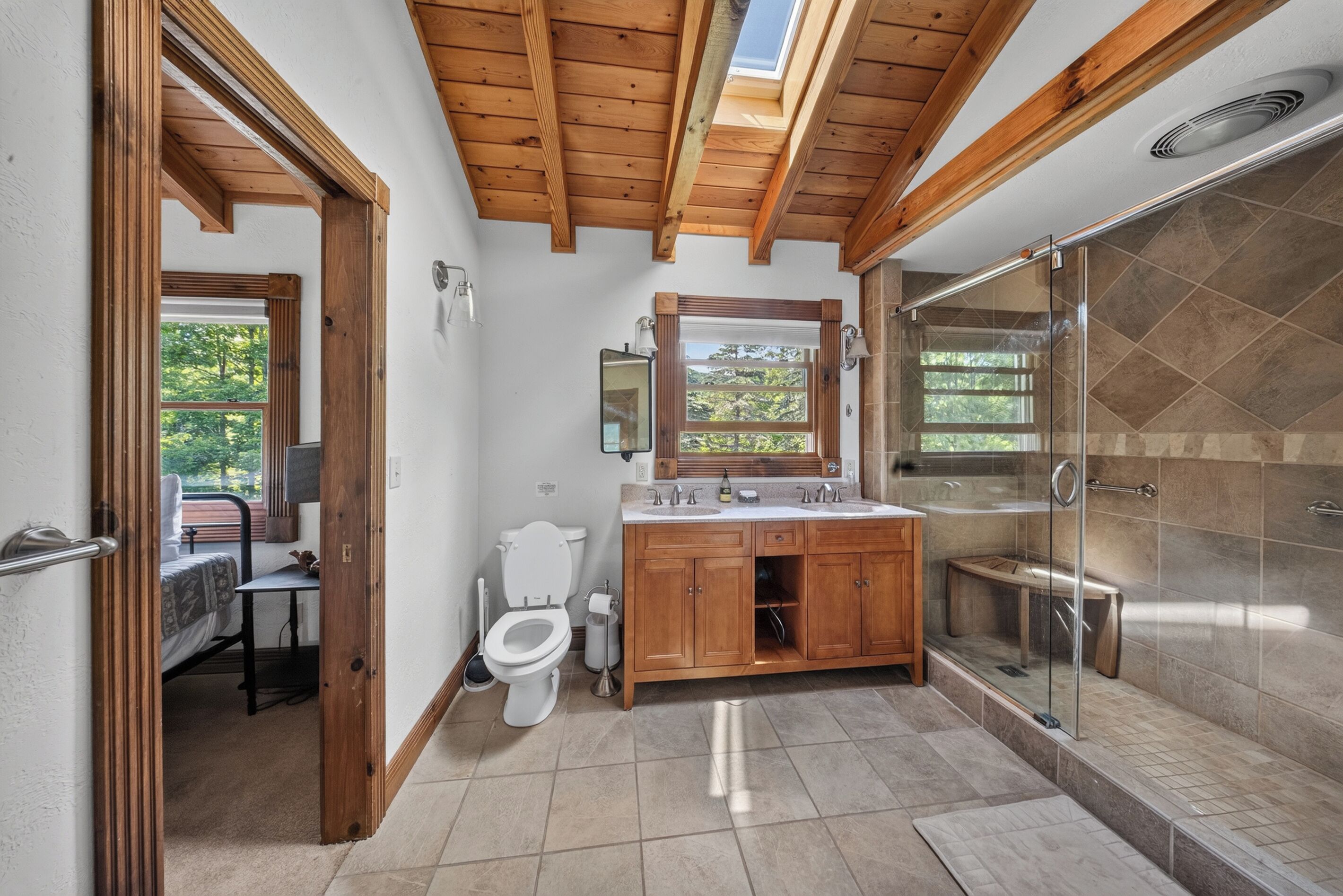 Een badkamer met douche, toilet, wastafel en dakraam.