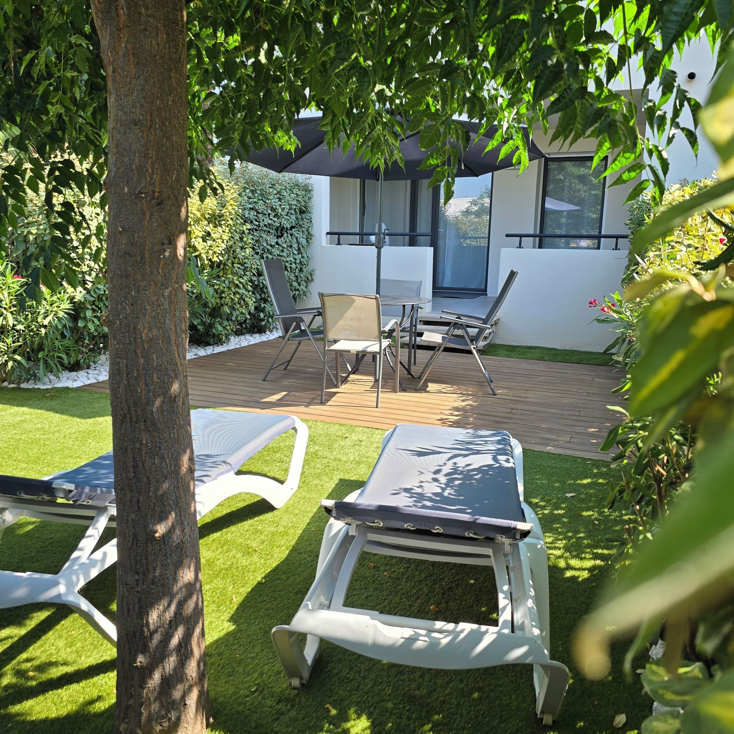 Een terras met lounge stoelen, een tafel en een overdekte zithoek.