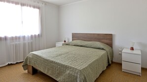 Een slaapkamer met een bed, nachtkastje en gordijnen bij het raam.
