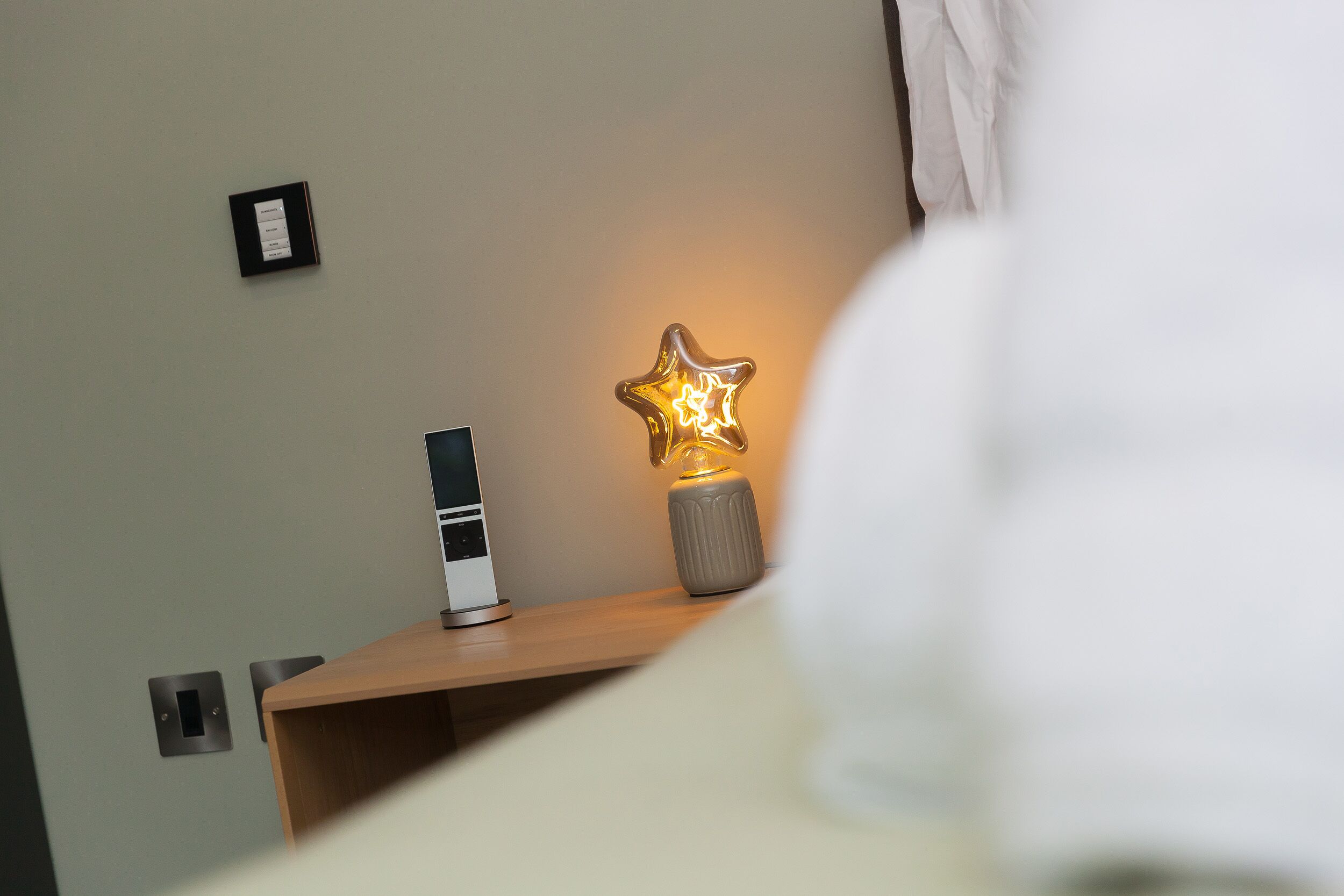 Ein Nachttisch mit einer sternförmigen Lampe und einem kleinen elektronischen Gerät.