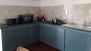 A compact kitchen with teal cabinets, a microwave, a stove, and a sink.