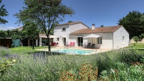 Une maison à deux étages avec une piscine, un espace salon extérieur et un jardin.
