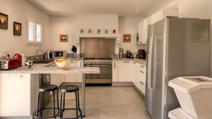 Une cuisine moderne dotée d’un îlot central, d’appareils électroménagers en acier inoxydable et d’un grand réfrigérateur.
