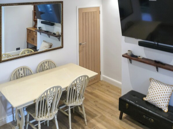 A dining area with a table and chairs, a television mounted on the wall, and a wooden door.