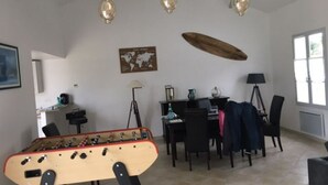 Una habitación con mesa de fútbol de mesa, una mesa de comedor con sillas, una lámpara y un mapa mundial en la pared.