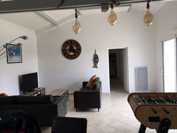 Un salon comprenant un canapé, une table basse, un téléviseur et un baby-foot.