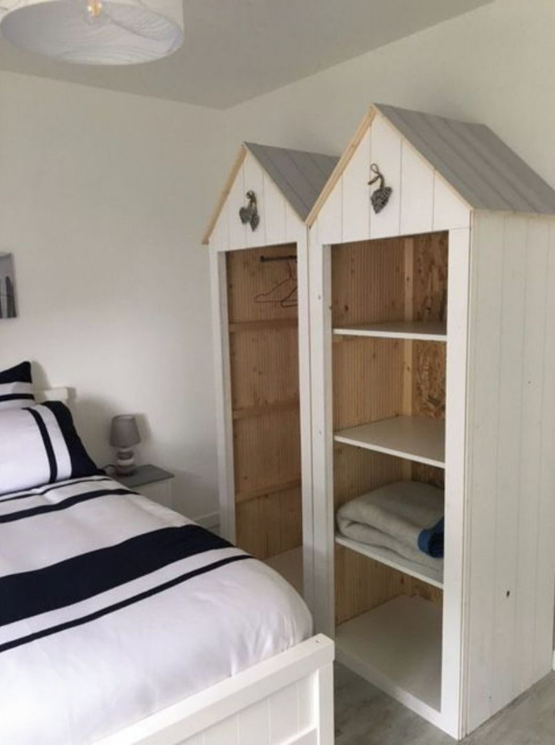 Une chambre à coucher comprenant un lit, une table de chevet et une armoire dotée d’un toit en pente.