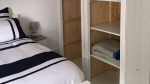 Un dormitorio con cama, mesita de noche y armario con diseño de tejado inclinado.