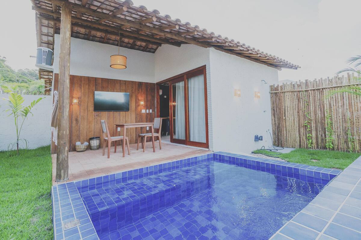 Una piscina con piastrelle blu, un pontile in legno e un televisore montato a parete.