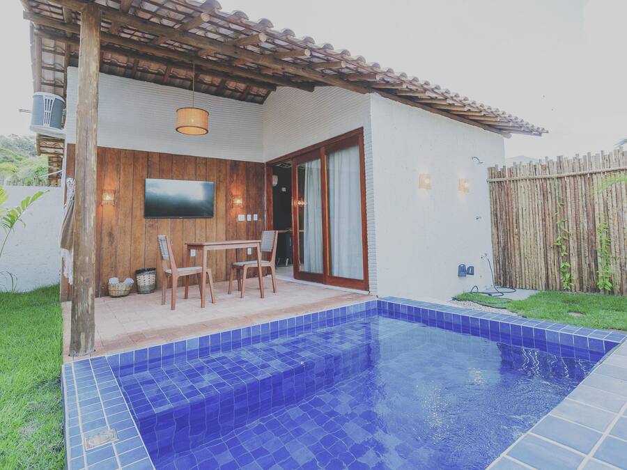 Piscina com azulejos azuis, deck de madeira e televisão fixada na parede.