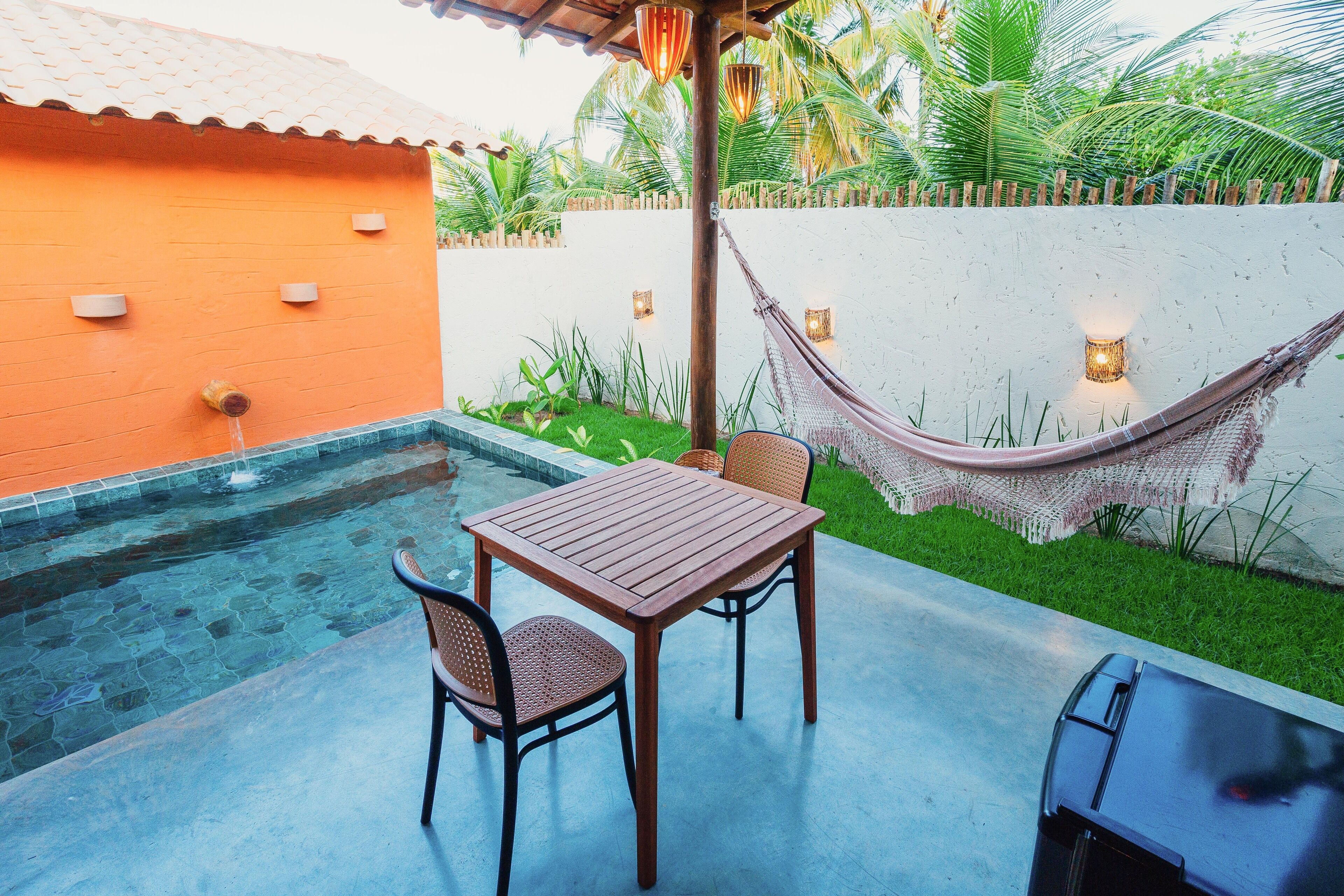 Een terras met een tafel, stoelen, een hangmat en een klein zwembad.