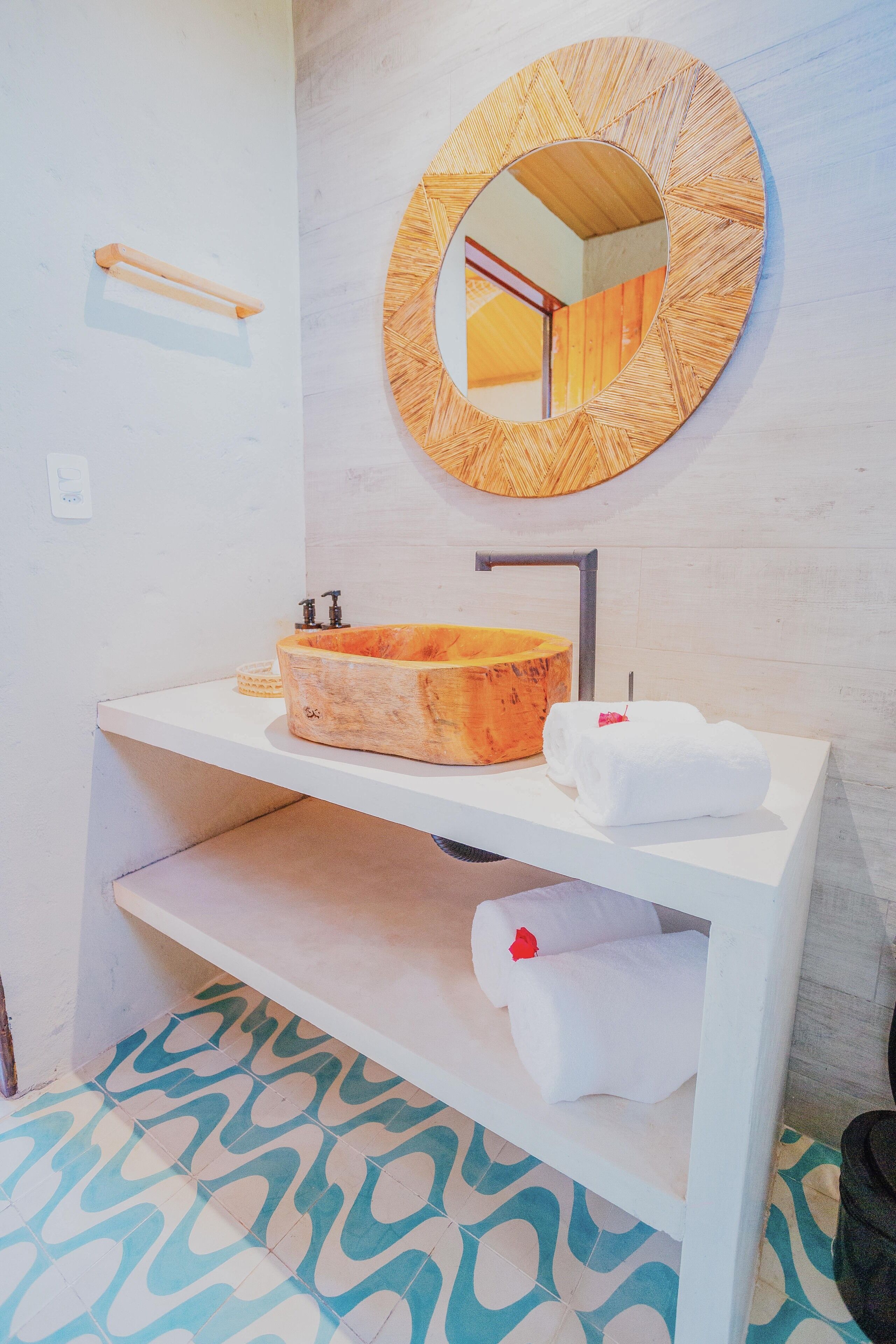 Un bagno con un lavabo in legno, uno specchio rotondo e un portasciugamani.