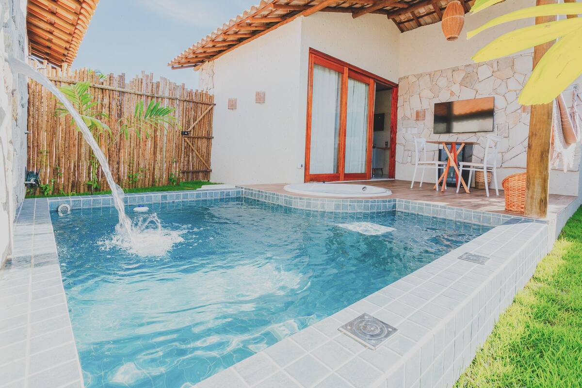 Una piscina con un muro in pietra e una recinzione in legno sullo sfondo.