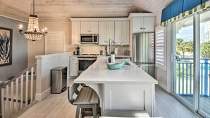 Una cocina moderna con armarios blancos, una isla central, electrodomésticos de acero inoxidable y un candelabro.