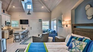 Un dormitorio moderno con una cama grande, un escritorio y una kitchenette.