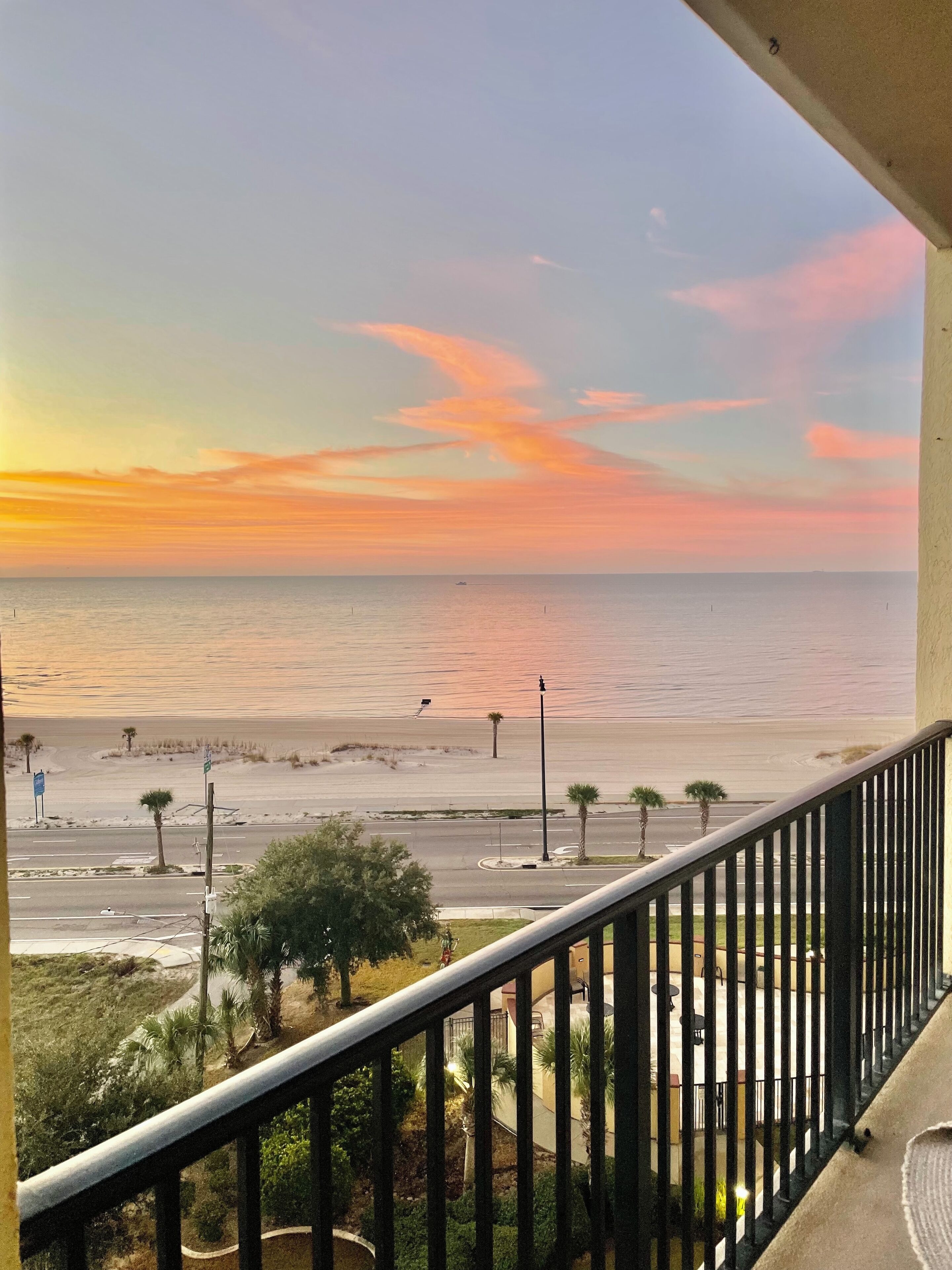 Ein Balkon mit Blick auf Strand und Meer bei Sonnenuntergang.