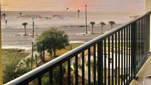 Un balcón con vista a la playa y al océano durante el atardecer.