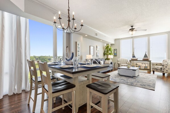 A spacious living room with a large dining table, comfortable seating, and a view of the outdoors.