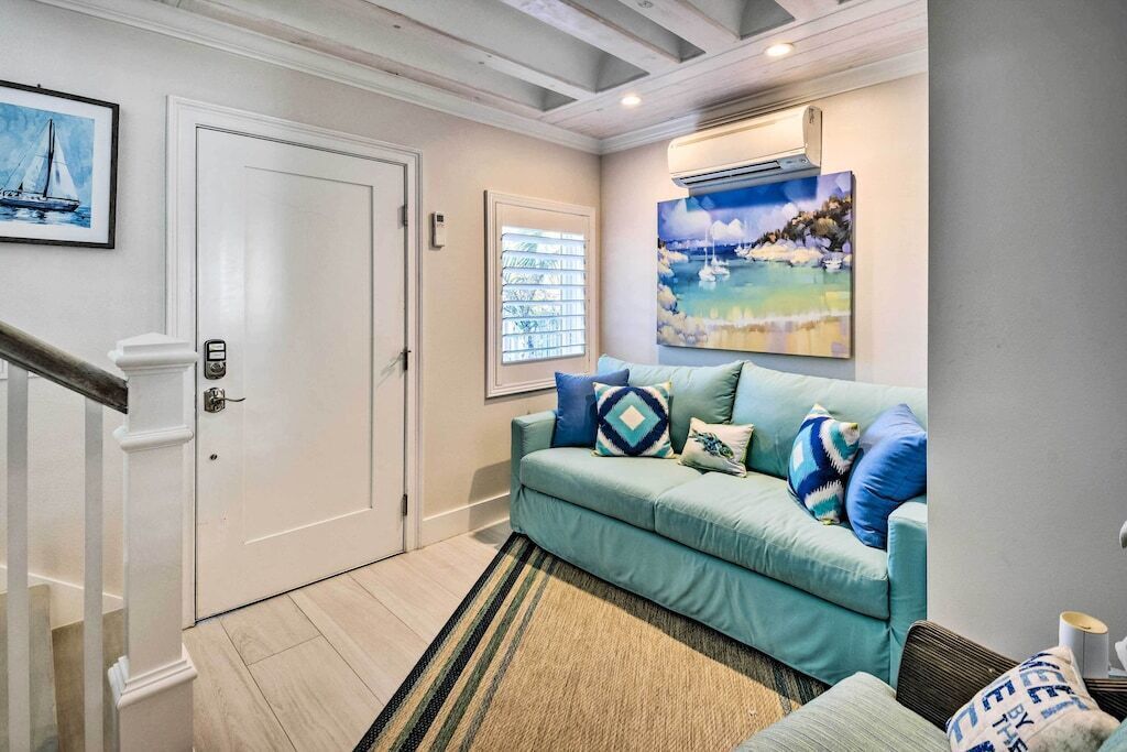 A living room with a teal sofa, a patterned rug, and artwork on the walls.