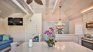 A modern kitchen with a large island, a dining area with a blue sofa, and a chandelier.