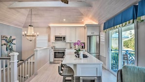A modern kitchen with white cabinets, a central island, and a chandelier.