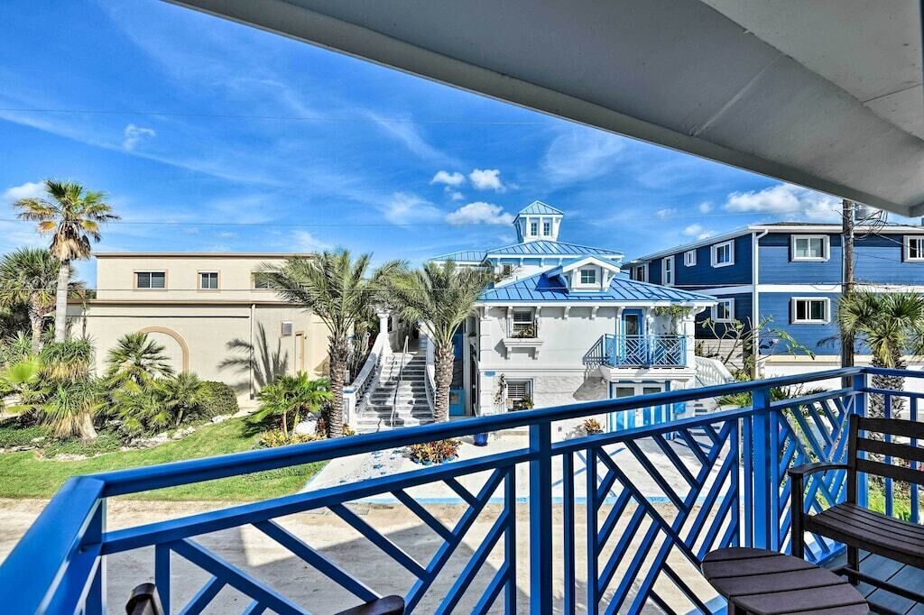 A balcony with a blue railing overlooking a building with a blue roof and a white facade.