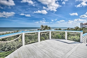 Enjoy breathtaking ocean views from this deck surrounded by lush greenery and palm trees.