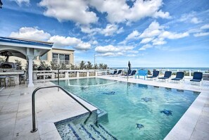 Relax by the pool surrounded by lounge chairs and a bar area.