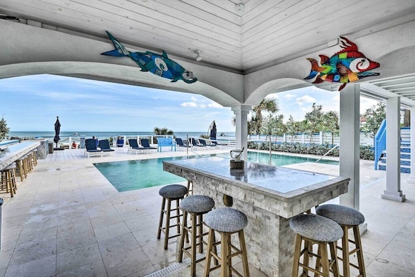 Relax by the ocean-view pool, surrounded by lounge chairs and a bar area.