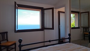A bedroom with a bed, a chair, a wardrobe, and a large window with a view of the sea. - Fantastic view, maximum relax and wellness. (Costa Paradiso)