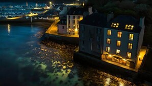 Une ville côtière de nuit, avec des bâtiments illuminés et un port de plaisance.