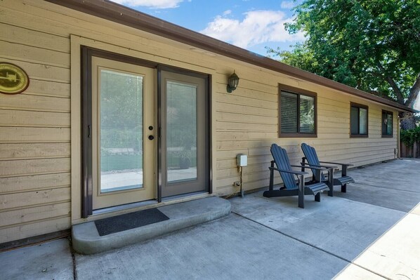 A motel with a beige exterior, two sliding glass doors, and a small porch with two Adirondack chairs. - Updated Eagle Home | Hot Tub + Walk to Downtown (Eagle)