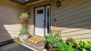 A house with a white door, a hanging flower basket, a welcome mat, and various potted plants. - Updated Eagle Home | Hot Tub + Walk to Downtown (Eagle)