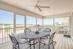 Relax in this serene outdoor seating area with a round table and four chairs, surrounded by a beautiful view of the water and distant buildings.