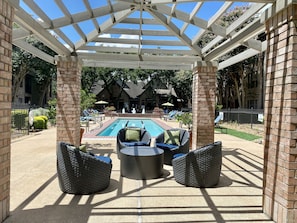 A covered outdoor pool area with lounge chairs and a pergola structure.