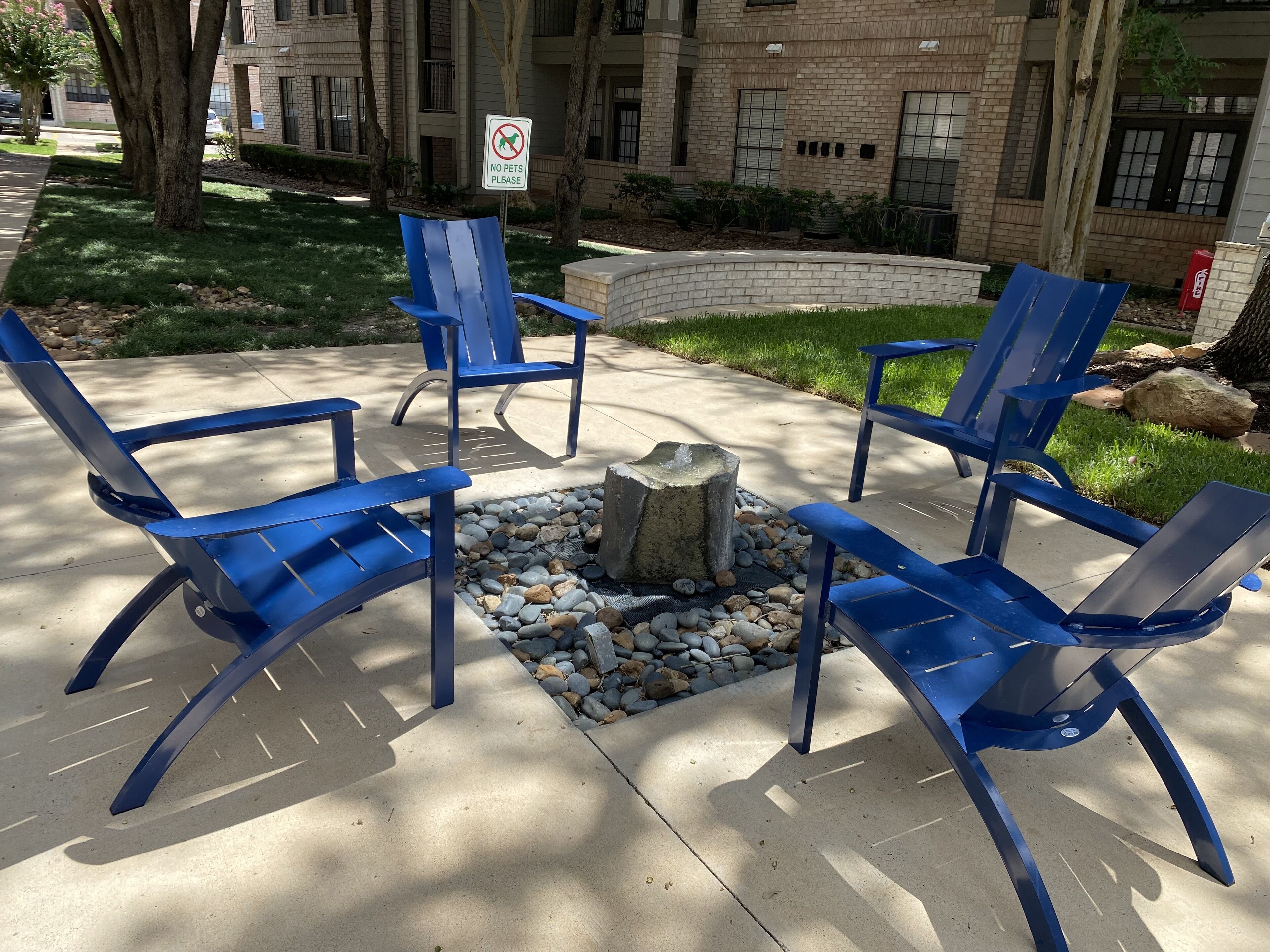 Outdoor seating with blue chairs arranged around a stone fire pit.