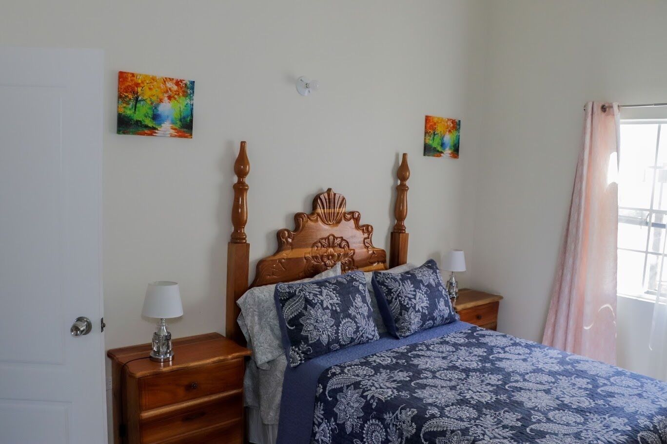 A bedroom with a wooden bed, two nightstands, and two wall-mounted paintings.