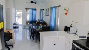 Una cocina moderna con microondas, estufa y comedor con sillas y mesa.