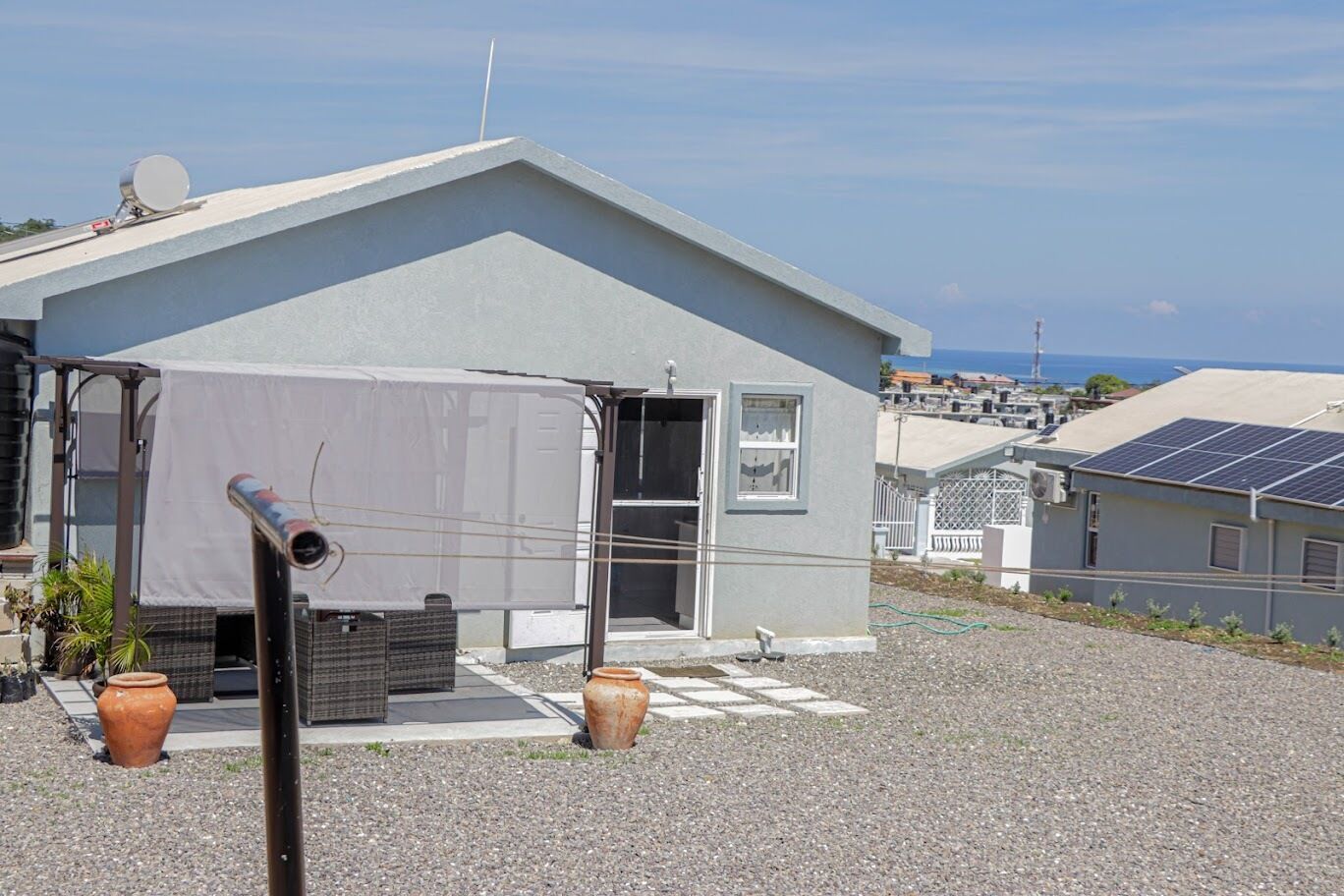 A small, single-story building with a sloped roof, a satellite dish, and a solar panel array.