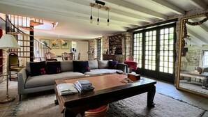 A spacious living room with a large sectional sofa, a wooden coffee table, and a staircase leading to an upper level. - Grand Cottage-Near Benodet-Heated Pool (Tréméoc)