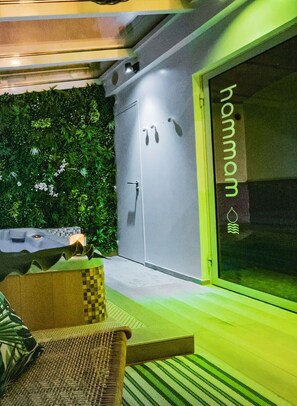 Relax and socialize in this serene outdoor space, featuring a seating area, lush greenery, and a large window.