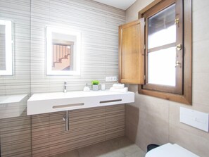 Een moderne badkamer met een grote spiegel, een houten kast en een raam.