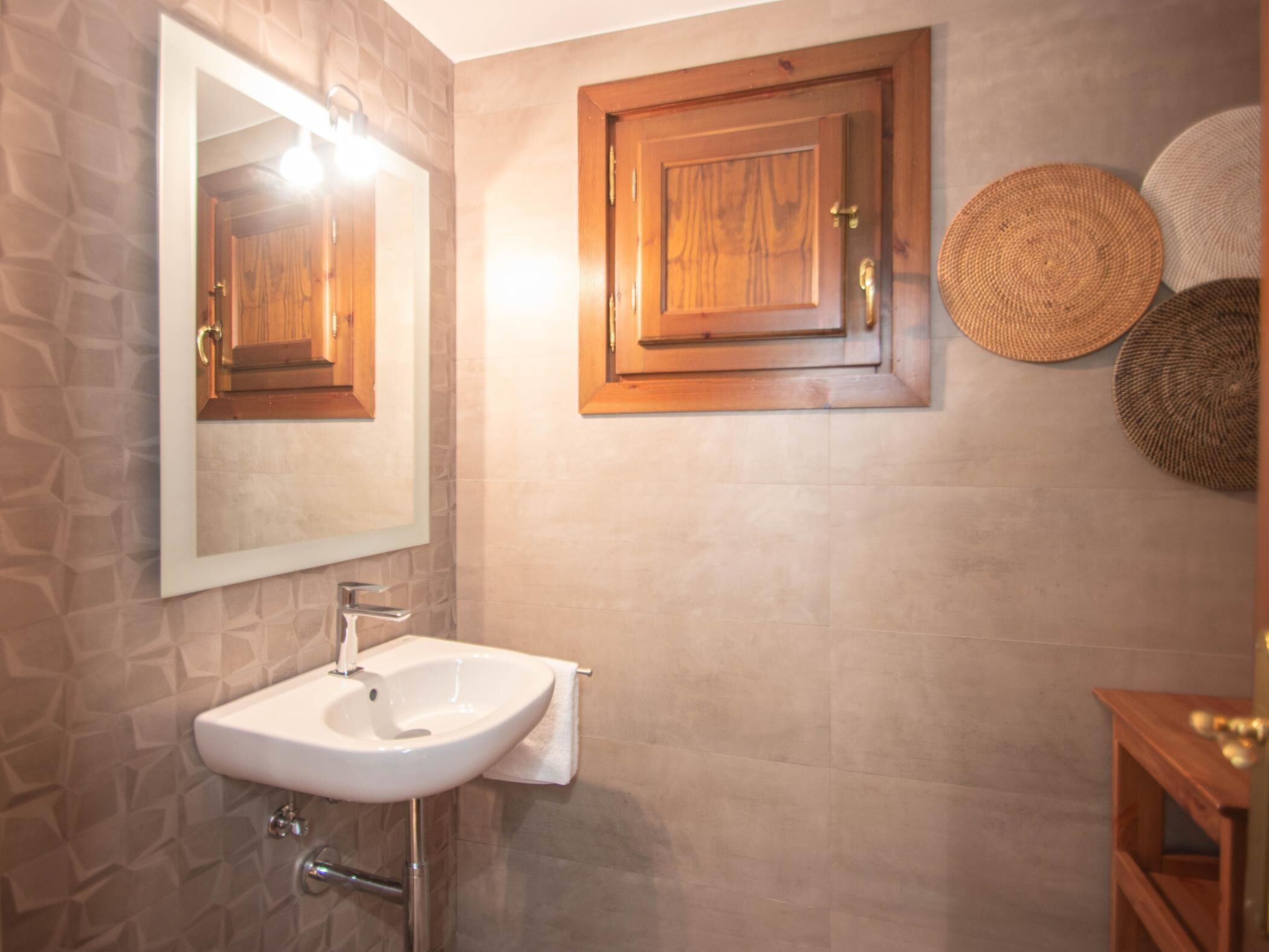 A bathroom with a white sink, a mirror, and wooden cabinets.