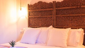 A bed with white bedding and a decorative headboard with intricate carvings.