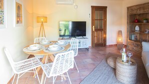 A dining area with a TV, white chairs, and a wooden table.